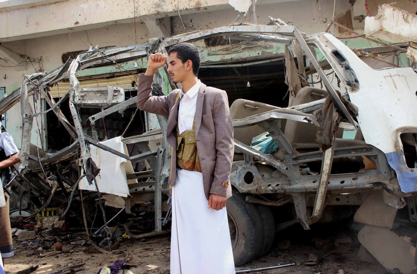 A Yemeni stands near a destroyed bus at the site of a Saudi-led airstrike a day after it hit the bus which was carrying children A Yemeni stands near a destroyed bus at the site of a Saudi-led airstrike a day after it hit the bus which was carrying children
