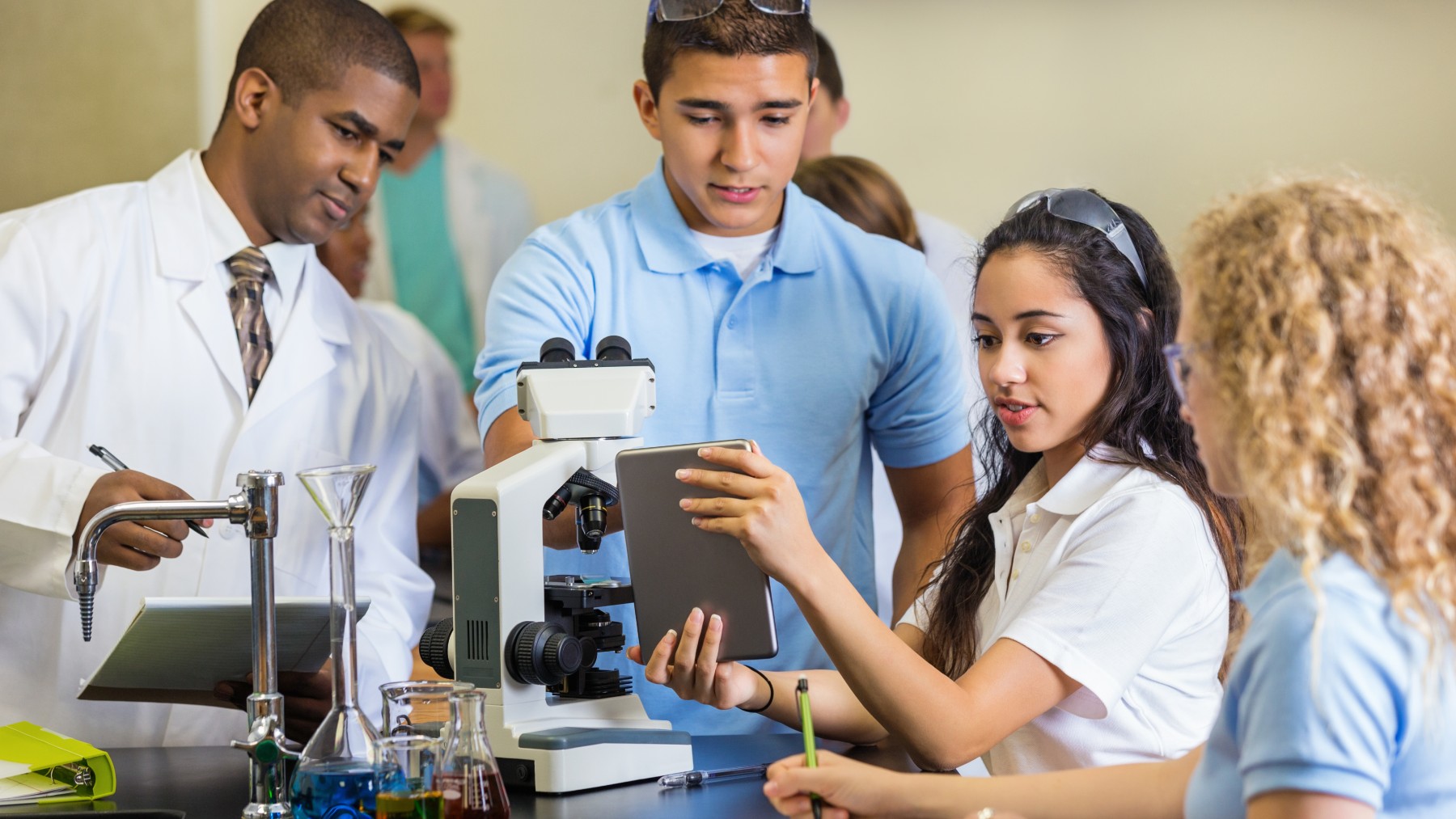 High school science teacher teaching students to use microscope