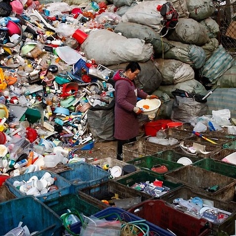 A worker sorts used plastics at a trash collection site in Changping district of Beijing, China