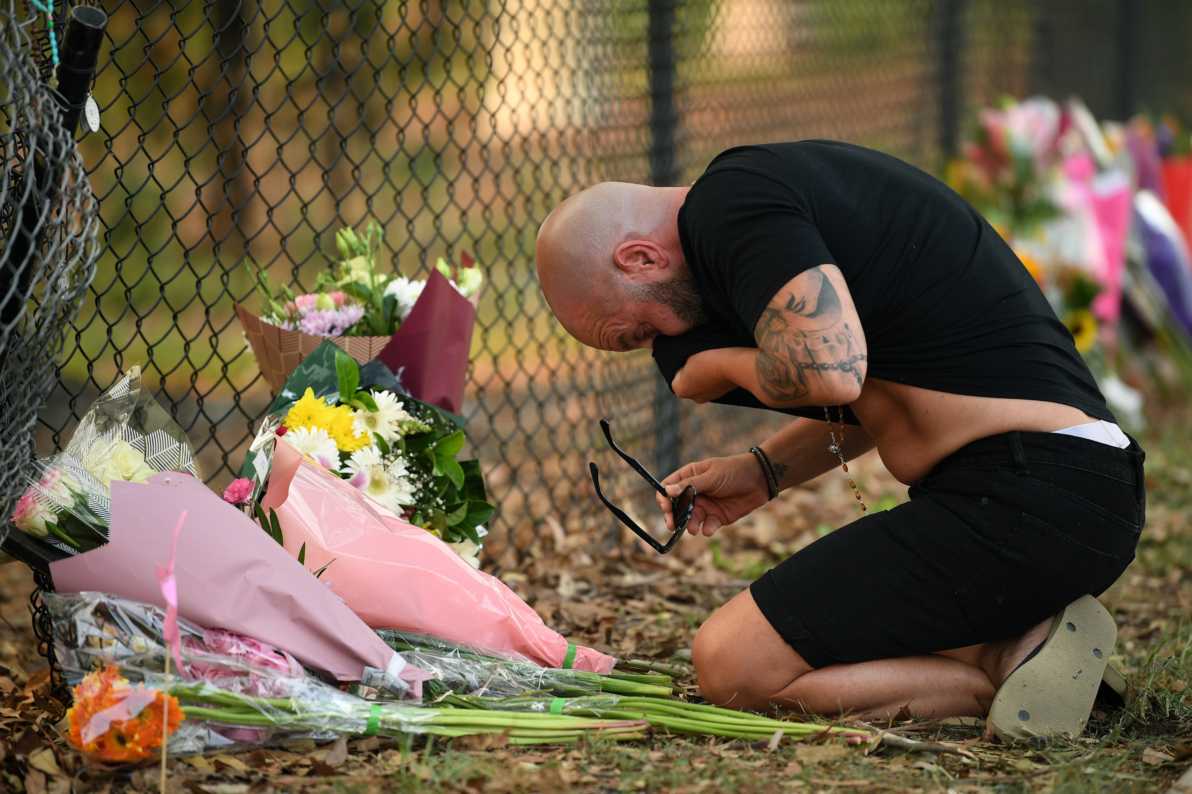 A man pauses near flowers placed at the scene where seven children where hit on a footpath by a four-wheel drive in the Sydney suburb of Oatlands
