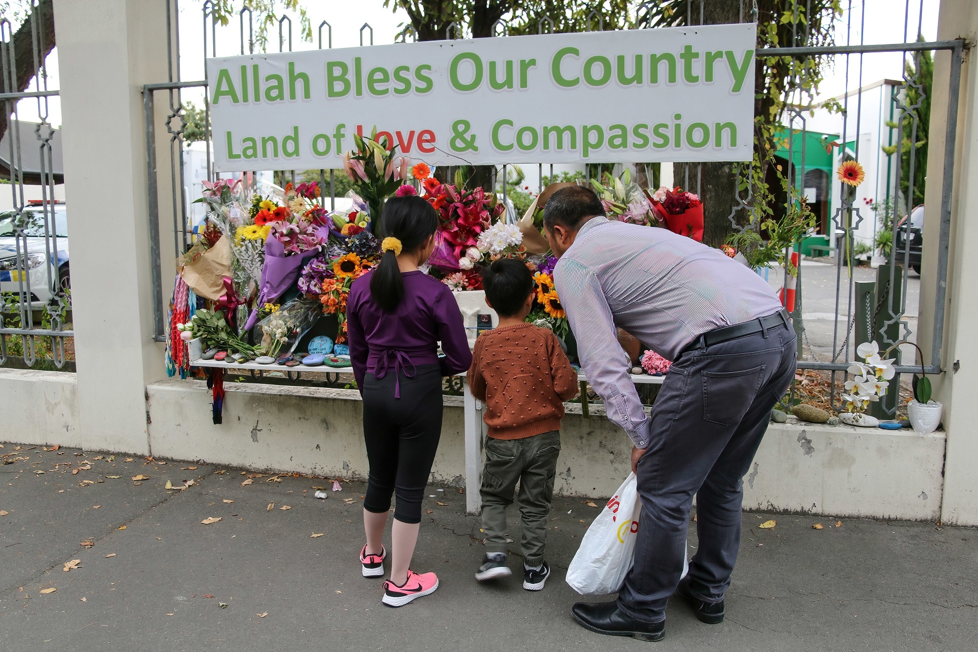A man and his children place flowers as a tribute outside the Al-Noor Mosque on 15 March 2021. 