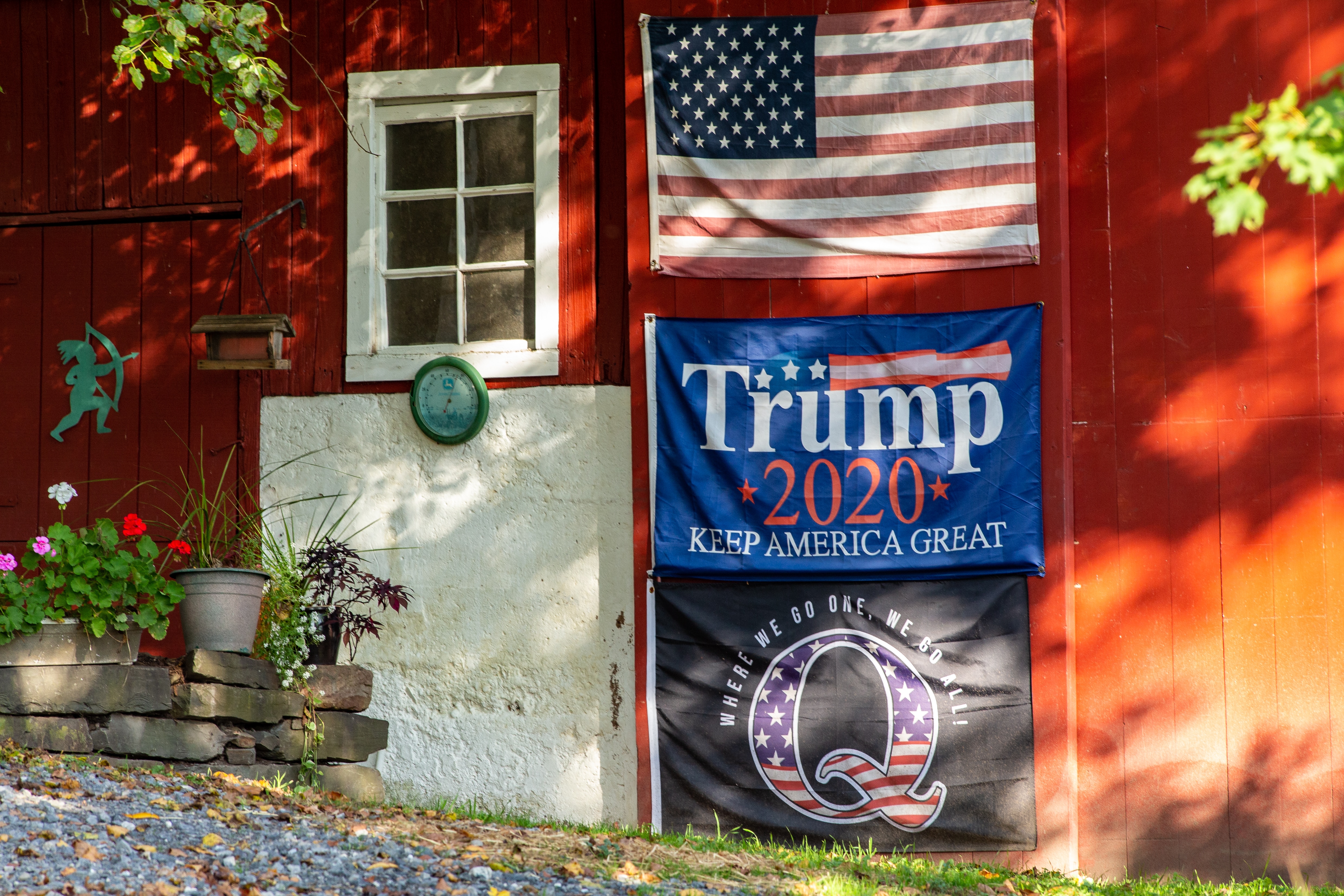 An American flag, a Trump re-election flag, and a QAnon flag are displayed on a barn in central Pennsylvania in October 2020.