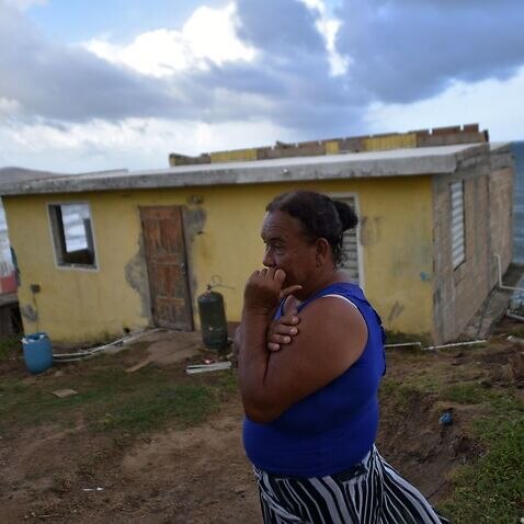 Maria Martinez stands next to her house which was damaged by Hurricane Maria in Puerto Rico