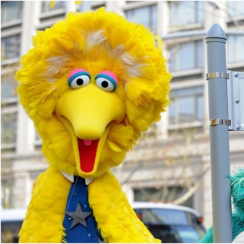 Big Bird (L) and other Sesame Street puppet characters pose next to a Sesame Street sign in New York City.