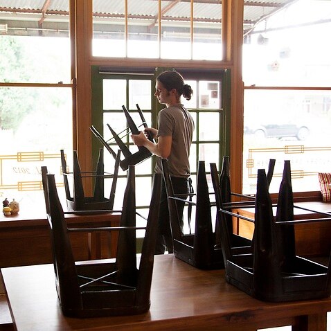 Waiter packing up cafe or restaurant chairs
