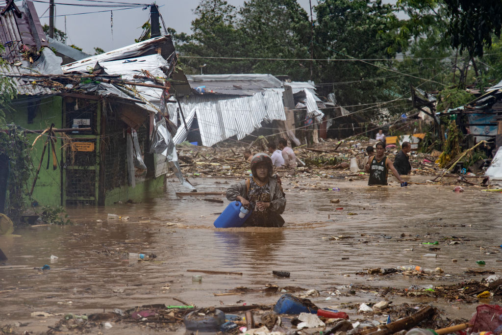 Residents wade across a flooded village, as Typhoon Vamco hits on November 12, 2020 in Rodriguez.