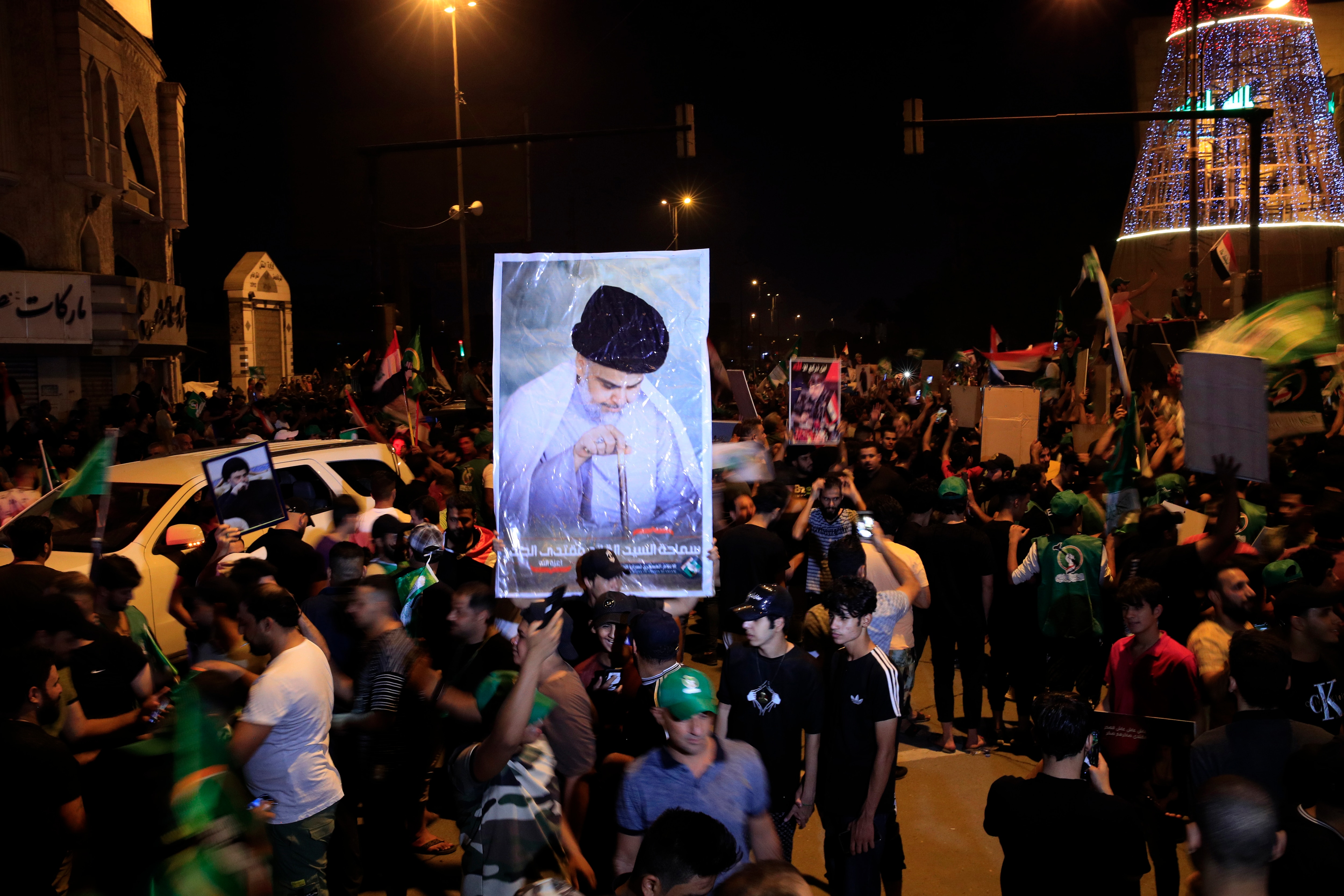 Followers of Shiite cleric Muqtada al-Sadr celebrate holding his posters, after the announcement of the results of the parliamentary elections in Tahrir Square, Baghdad, Iraq, Monday, Oct. 11, 2021. Iraq's Independent High Electoral Commission (IHEC) anno