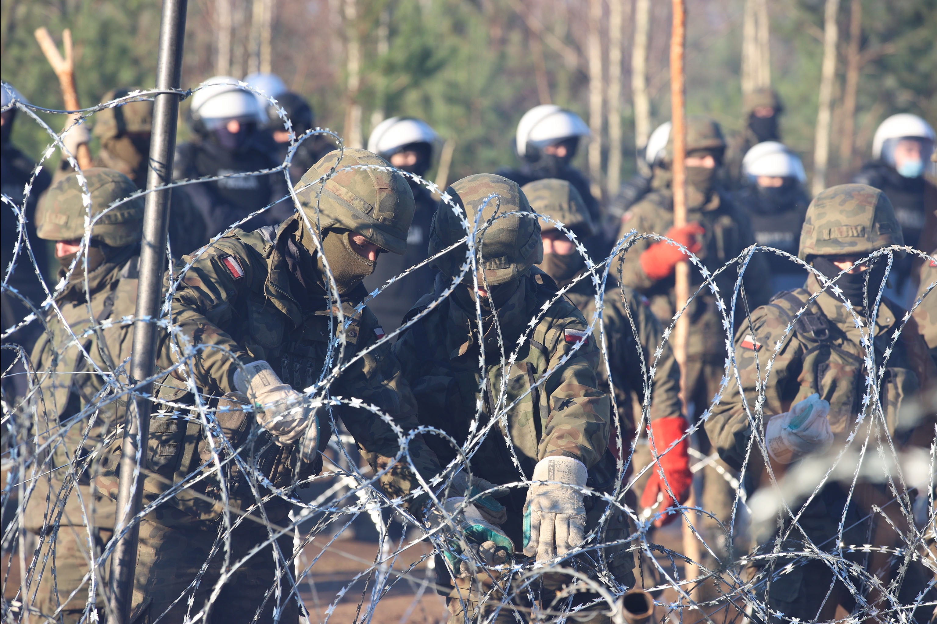 A handout picture shows Polish servicemen reinforcing the border line with barbed wire