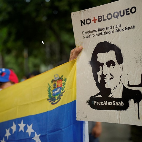 A woman holds a sign with the image of businessman Alex Saab who has been extradited to the U.S., during a demonstration demanding his release in Caracas. 