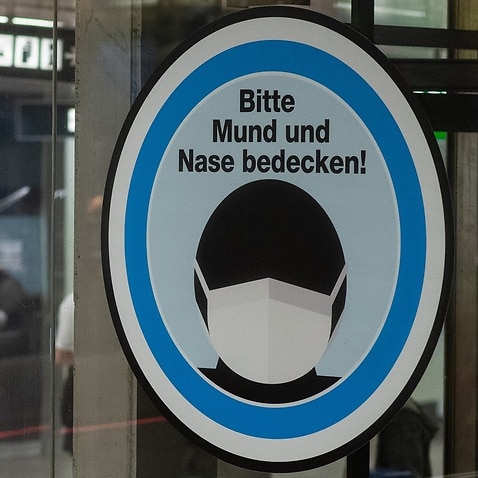 A sign reading Please cover your mouth and nose, at Karlsplatz underground station in Vienna, Austria