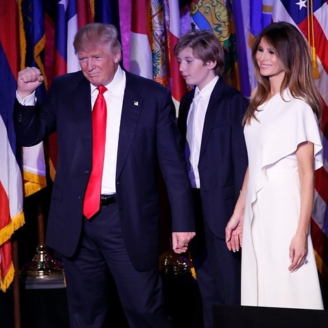 Donald Trump (L) gestures next to his son Barron (C) and his wife Melania Trump (R) as he delivers a speech on stage after winning November's US election 