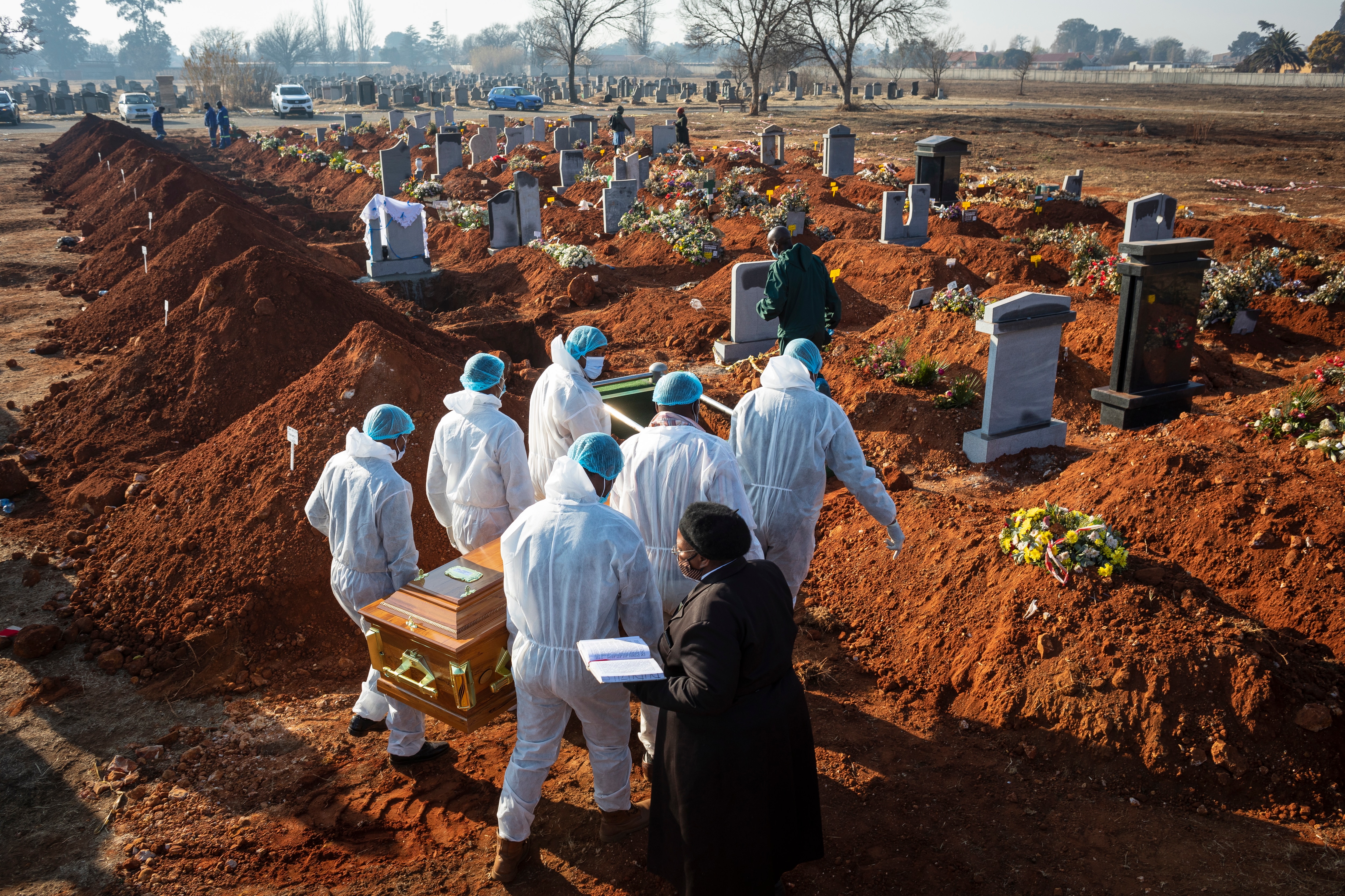 Family members wearing full PPE suits carry the remains of their elderly family member who died of COVID-19 in Johannesburg, South Africa.