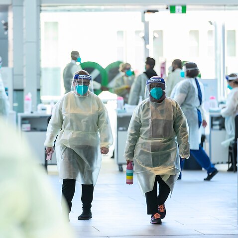 Health workers in full PPE prepare to vaccinate people at the Melbourne Museum.