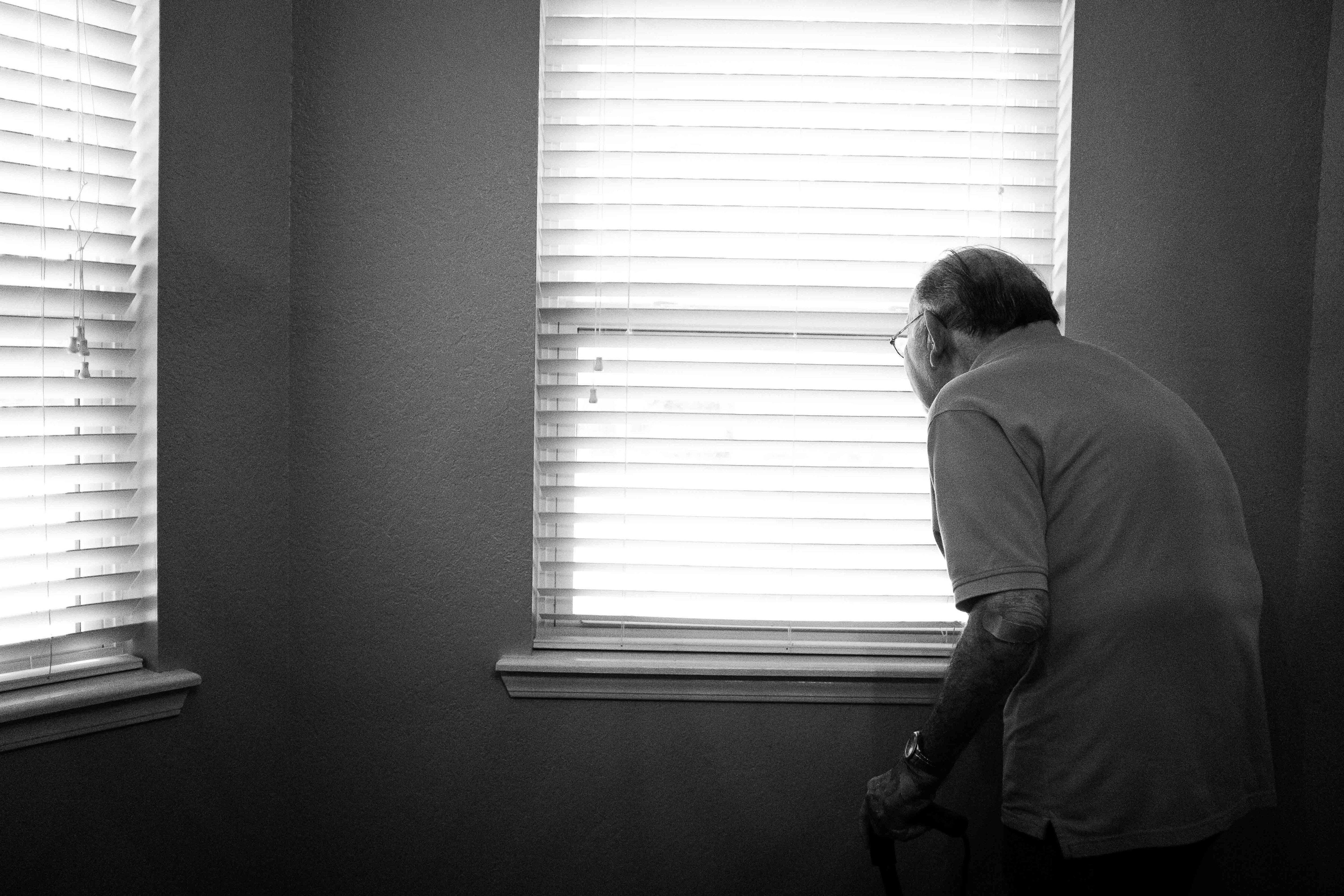 Elderly man standing in front of a window
