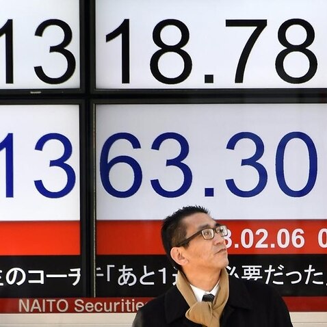 A man stands in front a stock market board in Tokyo