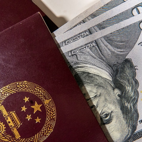 US Dollar banknotes folded in the passport of China.
