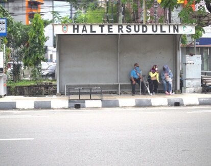Several people with a disability wait at a bus stop in Banjarmasin.