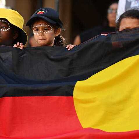 Young protestors hold an Aboriginal flag. 