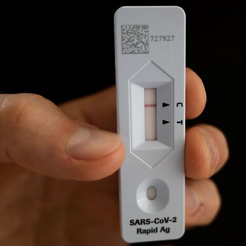 A generic image of person holding up a SARS CoV-2 Rapid Antigen Test showing a negative test result