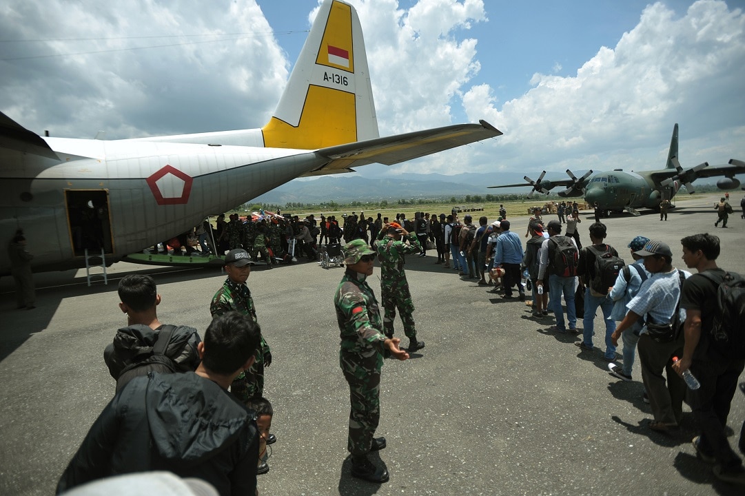 Residents wait to board a military plane for evacuation at the airport in Palu.
