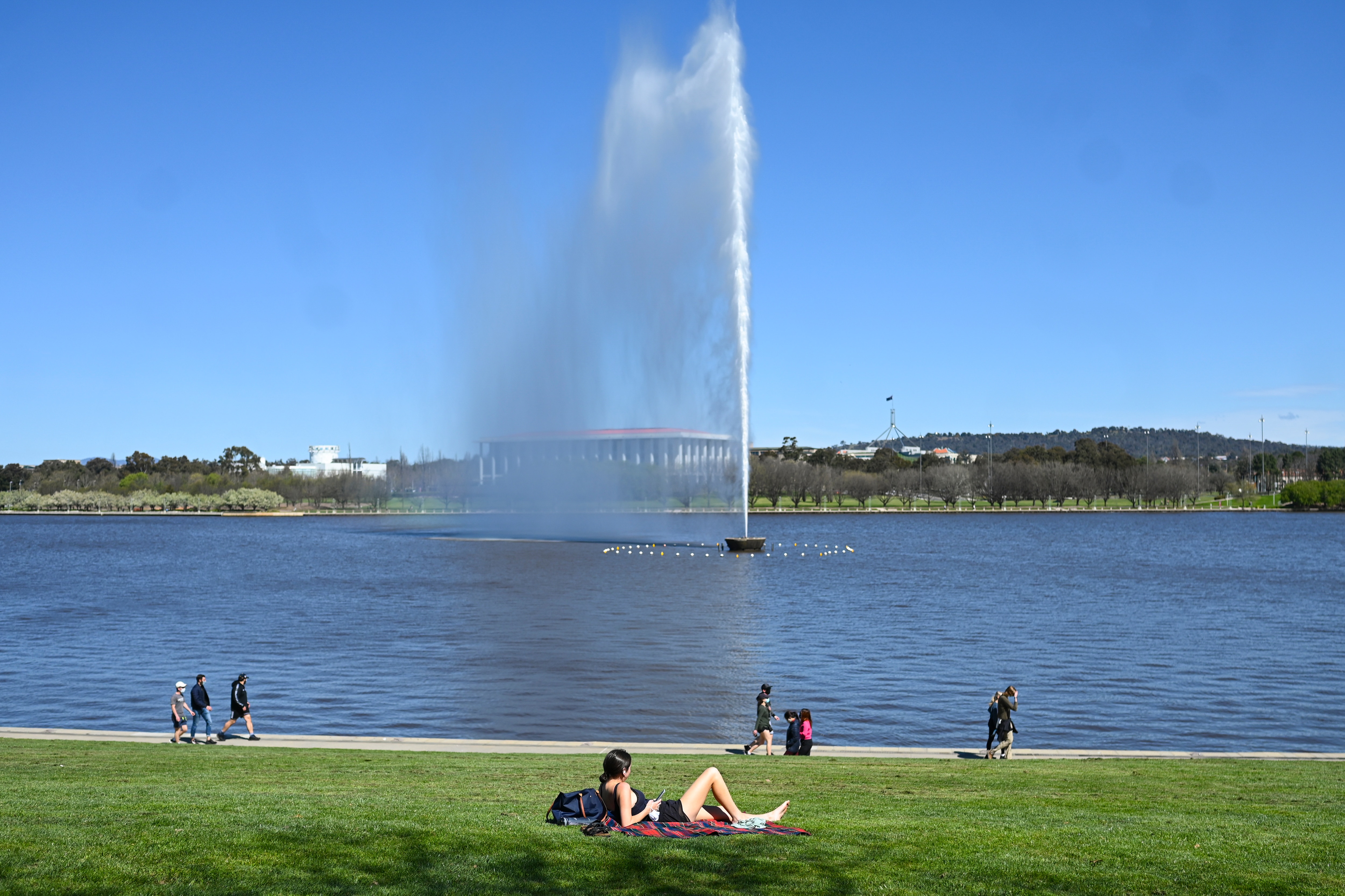 A resident enjoys the sunshine at the shore of Lake Burley Griffin in Canberra, Friday, September 17, 2021.