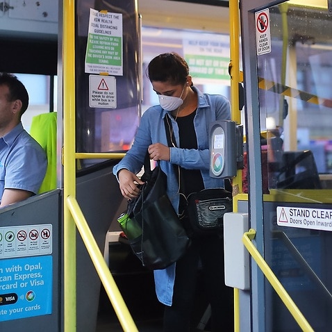 A woman wearing a mask as a preventative measure against the coronavirus disease (COVID-19) boards a public bus at Railway Square bus station in Sydney, Wednesday, April 1, 2020. (AAP Image/Steven Saphore) NO ARCHIVING