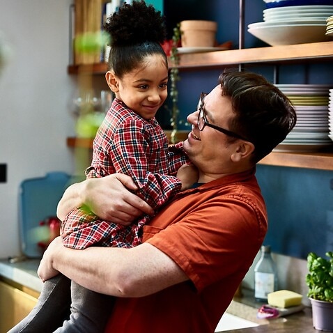 Man holding adopted daughter in kitchen