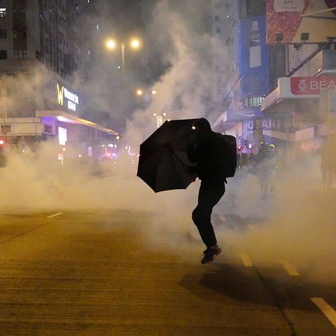 A protester holds an umbrella as police fire tear gas during a demonstration in Hong Kong early on New Year's Day.