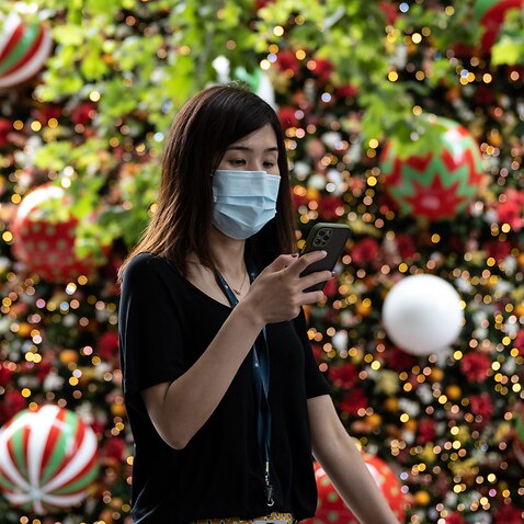 A woman wearing a  face mask walking past the Martin Place Christmas Tree in Sydney on 18 December, 2020. 