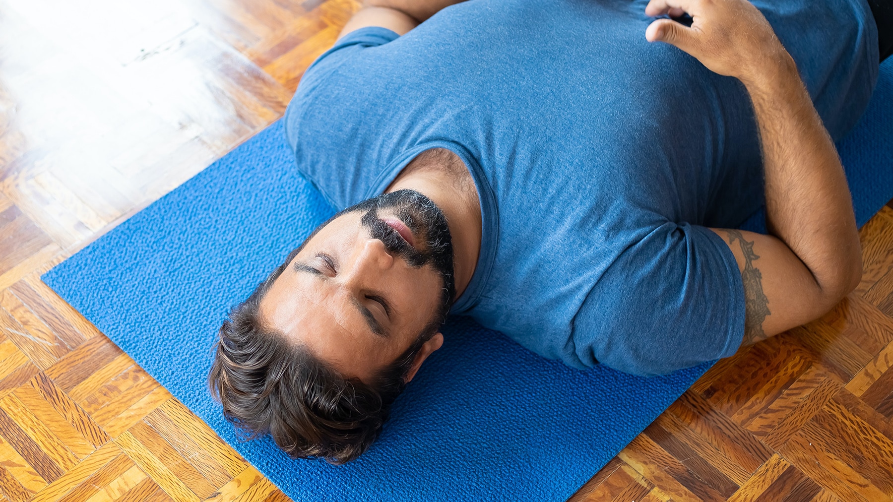 Man with beard lying on blue yoga mat