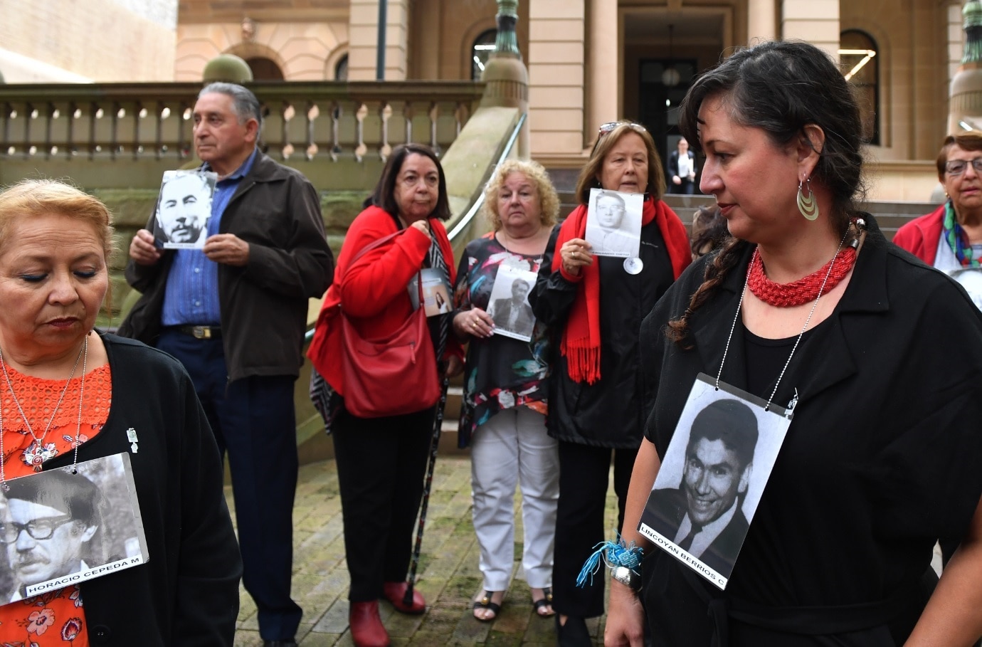 Members of the Chilean Australian community from the National Campaign for Truth and Justice in Chile, Australia wear pictures of some of the victims.