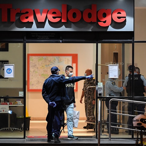 Guests under police guard depart the Travelodge Hotel in Surry Hills on 25 August, 2020 in Sydney.