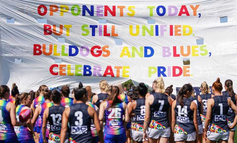 Players run through the pride banner during the Round 3, 2020 AFLW match between the Western Bulldogs and Carlton.