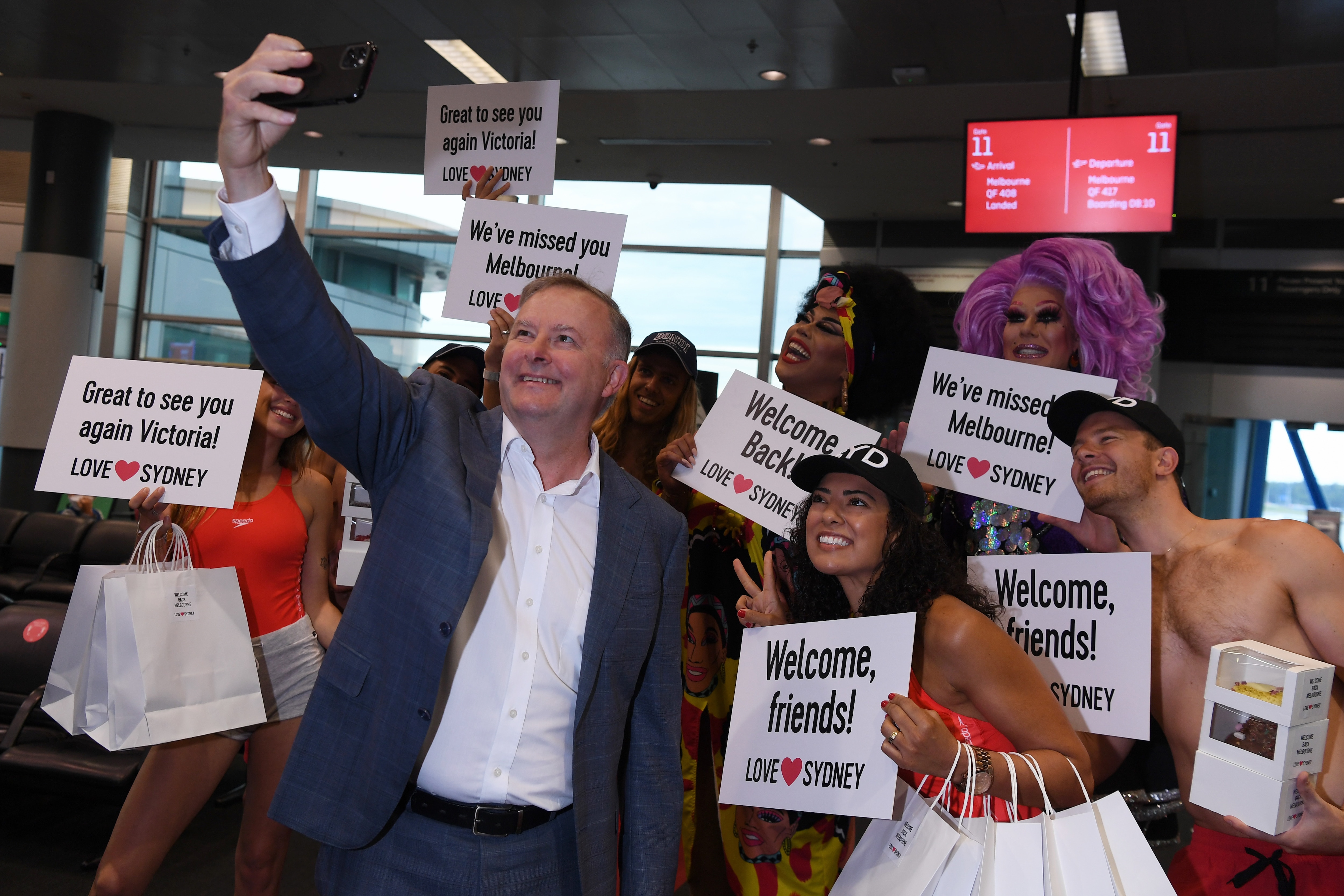 Anthony Albanese takes a selfie with the welcoming entertainment as passengers disembark the first Qantas flight from Melbourne after NSW reopened its border.