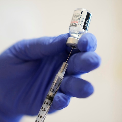 A Pfizer COVID-19 vaccine dose is drawn from a vial.