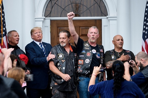 Mr Trump listens as supporters cheer following the pledge of allegiance during a Bikers for Trump event at the Trump National Golf Club .