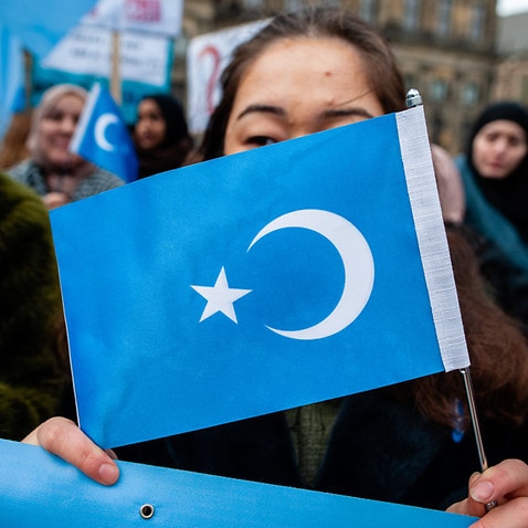 A woman holds a flag at a demonstration in support of Uighurs 