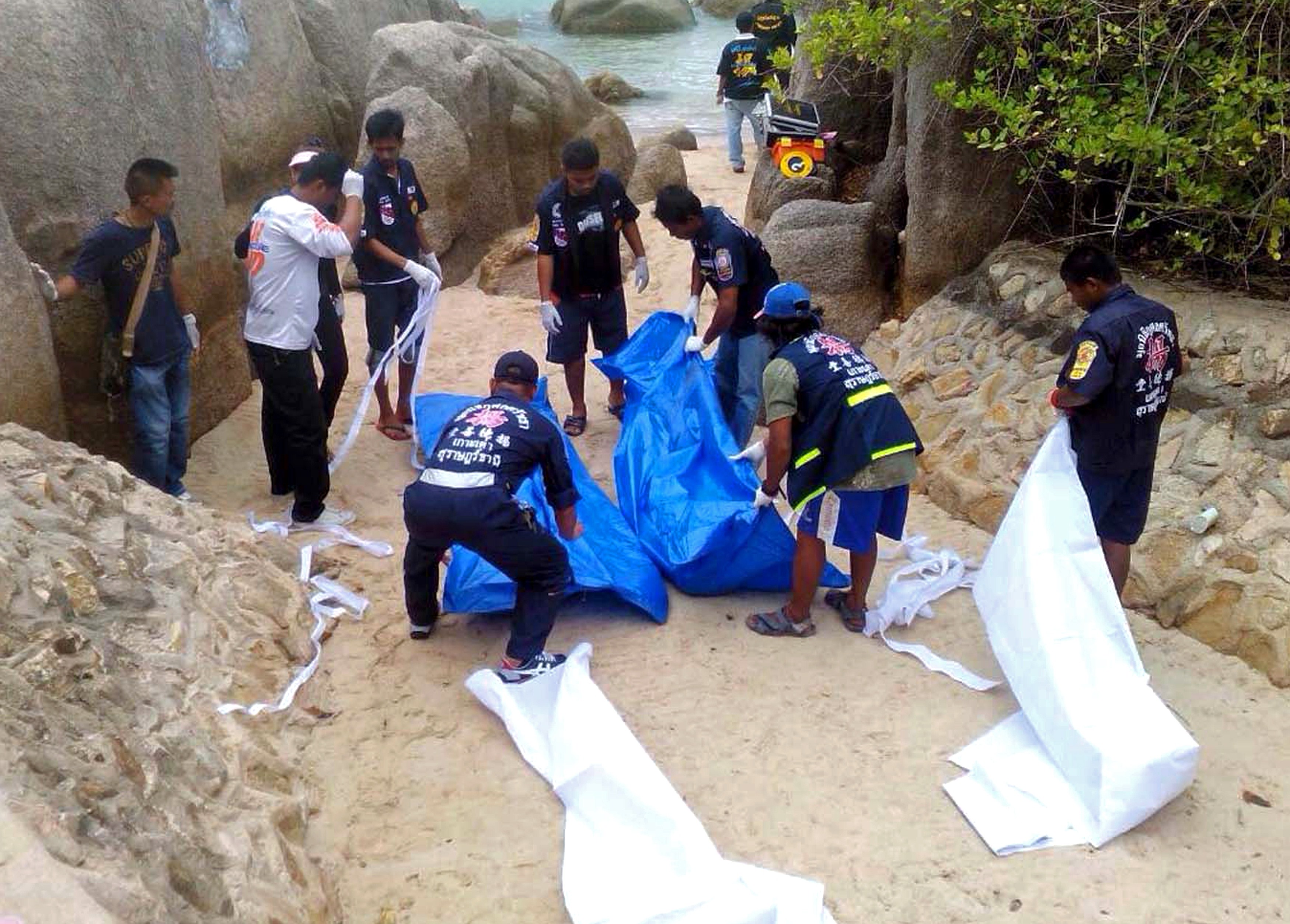 Thai workers carry the bodies of two British tourists on Koh Tao.