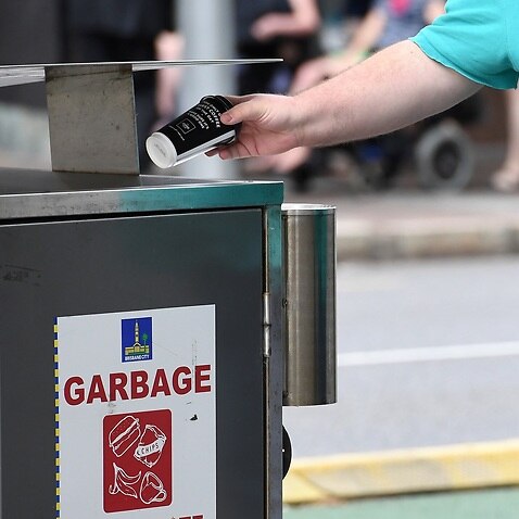 A man disposes of a coffee cup into a rubbish bin in Brisbane.               