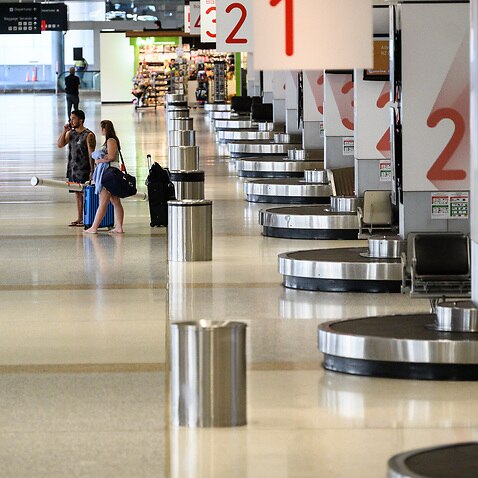 Passengers in an usually quiet baggage arrivals area at Sydney Domestic Airport, Friday, March 20, 2020.