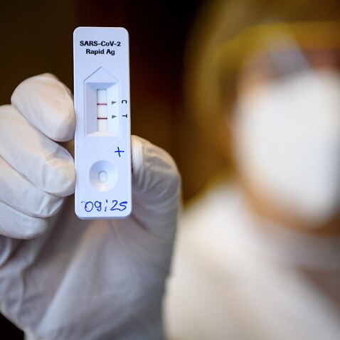 A health worker shows a positive result from a Rapid Antigen Test.