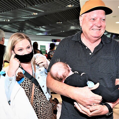Col holds his grandson Ted for the first time after greeting him and mother Lauren from an early morning the first flight from Melbourne to Brisbane. 