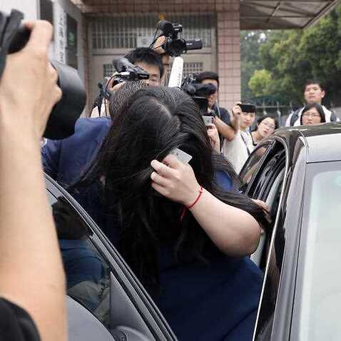 Crown Resorts employee Jiang Ling, center, hides her face as she leaves the Baoshan District People's Court after attending her trial in Shanghai 