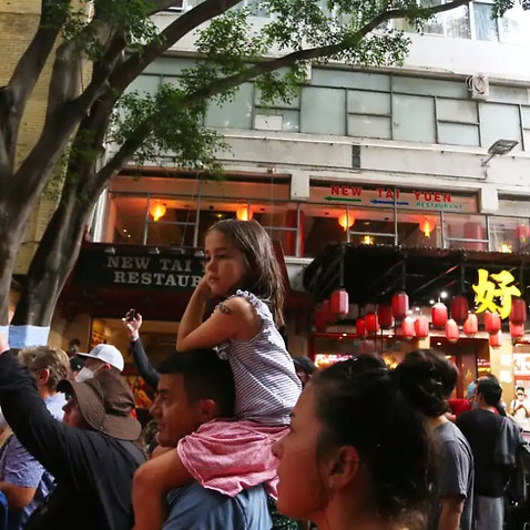 تعدادی از مردم در حال تماشای نمایش خیابانی در محله چینایی‌ها در ملبورن، ۲۹ جنوری ۲۰۲۲.