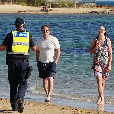 Police officers inform beachgoers that the beach is closed at Brighton Beach in Melbourne.