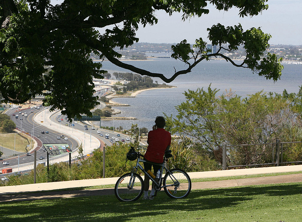 Perth, AUSTRALIA:  A man rests on his bike (C-below), as he looks out from Kings Park onto Perth's Swan River and foreshore, 15 October 2006.