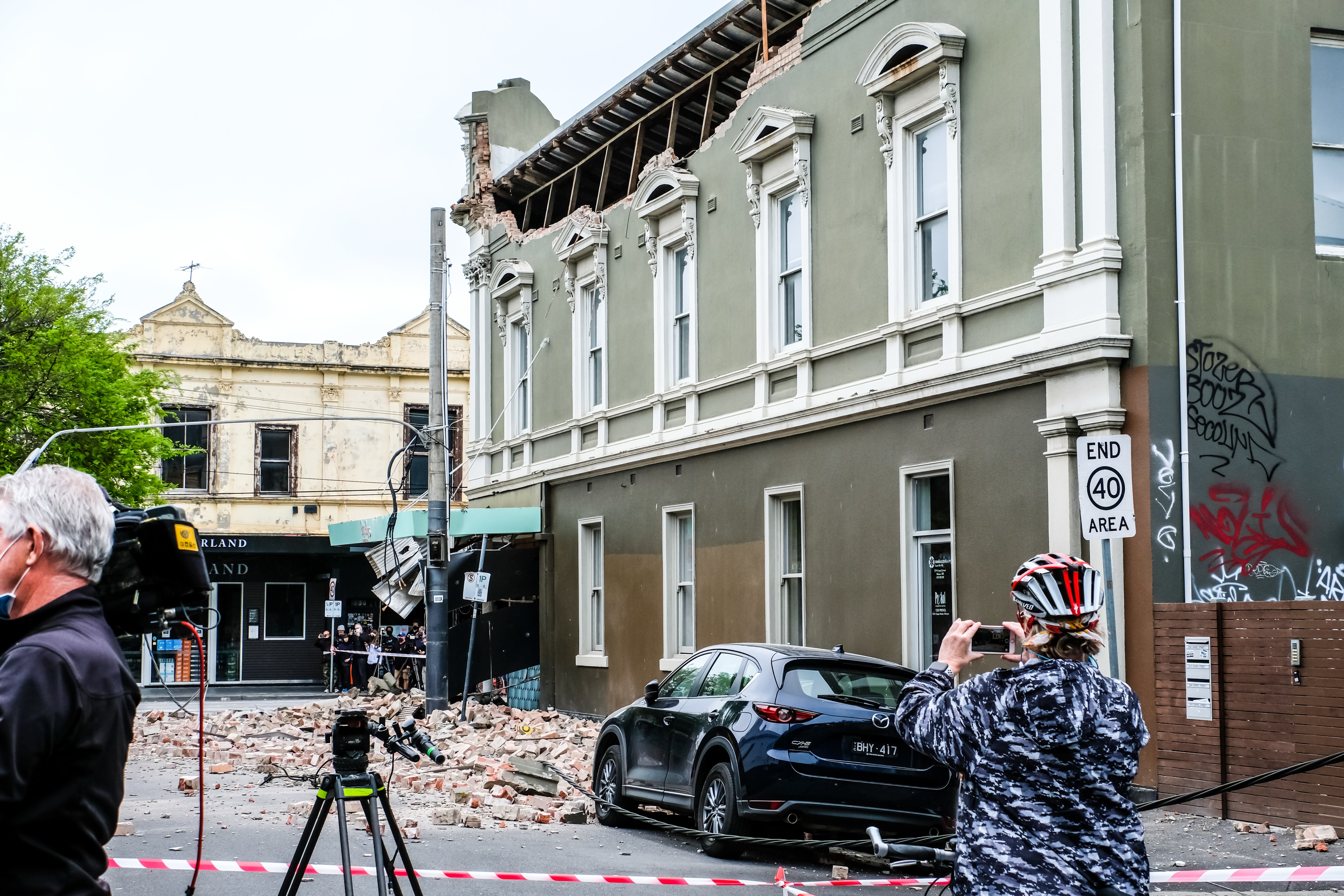 A woman taking photos of the damage caused by an earthquake in Melbourne during the aftermath.