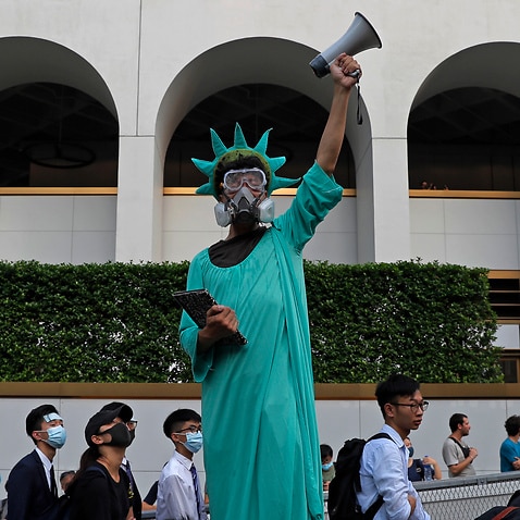 A protester dressed as the Statue of Liberty poses as people march past from Charter Garden to the U.S. Consulate in Hong Kong,