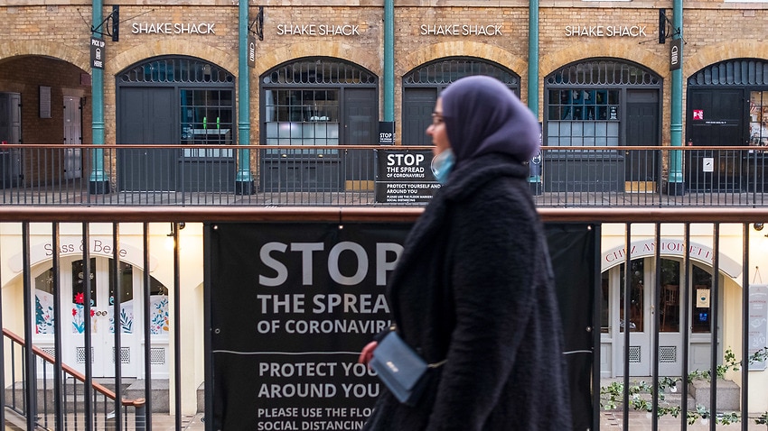 A woman walks past a COVID-19 sign inside Covent Garden, London