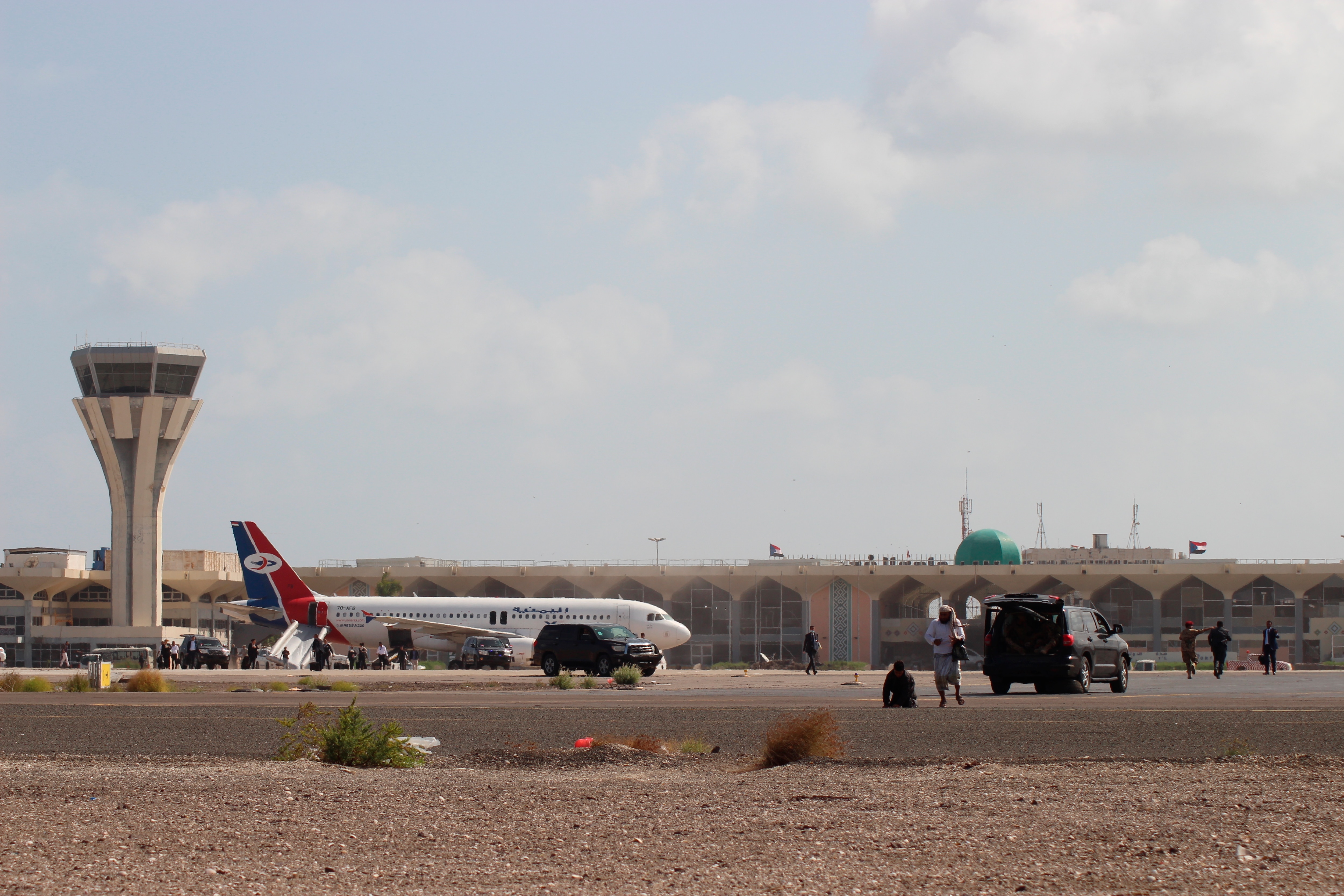 Bystanders stand near the runway of Aden airport shortly after the explosion.